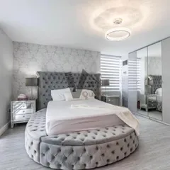 For a truly unique bedroom, consider a statement piece like this round, tufted bed. Paired with mirrored furniture and a textured wallpaper, this design creates a glamorous, Hollywood-regency-inspired look that is pure luxury.