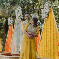 A sweet, romantic moment between the couple at their Haldi. The colorful, geometric backdrop made of marigold and tuberose strings adds a modern twist to the traditional ceremony decor.
