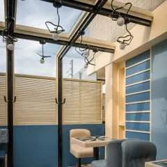 In contrast to the vibrant red zones, we designed this calmer blue section at Masala. The space features a glass ceiling and custom bird-like light fixtures, creating an airy, conservatory-like feel for daytime dining.