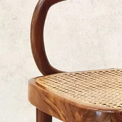 The beautiful curve of a bentwood chair, crafted from a single piece of solid teak. This technique requires skill and patience, resulting in a seamless and strong form.