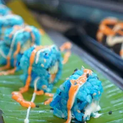 We bring a world of flavour to your table with creativity and flair. These vegetarian sushi rolls, made with naturally colored blue rice, are a testament to our innovative approach to global cuisine, offering a visually stunning and delicious bite.