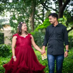 This couple holds a pair of baby shoes as they walk through a park, a simple and sweet prop to signify their growing family.
