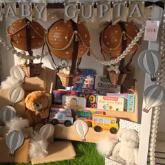 Up, up, and away! This whimsical hot air balloon themed gift includes a personalized bookshelf filled with classic stories and toys, designed to spark a lifetime of imagination for Baby Gupta.