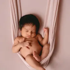 A simple yet powerful pose using a fabric hammock. This technique safely supports the baby while creating a beautiful, suspended look against a clean backdrop.