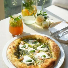 Another beautiful shot of our basil pesto pizza, enjoyed in the sunlit corner of our cafe. This pizza is a true testament to our farm-to-table philosophy.