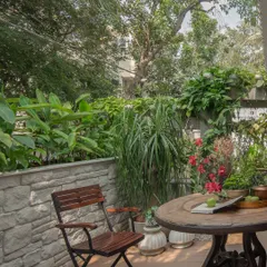 This outdoor patio is designed to be an extension of the living room. Simple wooden furniture sits amongst lush greenery, creating a perfect spot for a morning coffee or evening conversation.