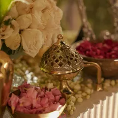 A close-up of a vintage brass incense burner, surrounded by bowls of fresh rose petals and fragrant jasmine. These traditional elements add a sensory layer to the decor, creating a truly immersive experience.