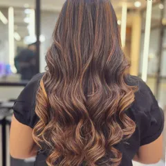 We specialize in creating gorgeous, voluminous waves. This look was achieved with expert styling to enhance the hair's natural texture and the beautiful dimension from the balayage highlights.