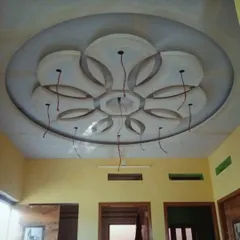 An in-progress view of an intricate floral medallion design for a ceiling centerpiece. This shows the raw POP and gypsum work before the final finishing and painting, highlighting the detailed craftsmanship.