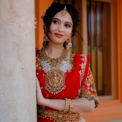 A classic pose, leaning against a pillar. This shot showcases the beautiful embroidery on the blouse and the traditional elegance of the entire bridal ensemble.