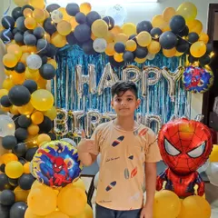 A happy birthday boy with his Spiderman-themed decoration. This setup uses a yellow and black color scheme with a blue shimmer curtain, creating a unique look for the popular superhero theme.