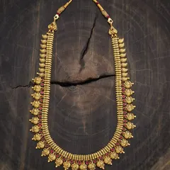 A classic kasu-style haram or long necklace. This piece features a traditional coin design with intricate carvings, set in a rich gold tone with red stone accents for a timeless appeal.