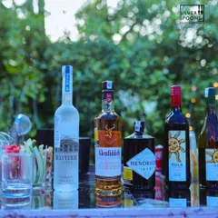 A well-stocked bar at an outdoor birthday party, featuring a selection of premium spirits like Belvedere, Glenfiddich, and Hendrick's Gin.