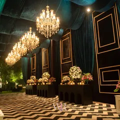 We designed this dramatic entrance corridor with a bold black-and-white chevron floor, deep teal velvet walls, and a procession of crystal chandeliers. This setup created a high-impact transition into the main event space for a glamorous engagement party.