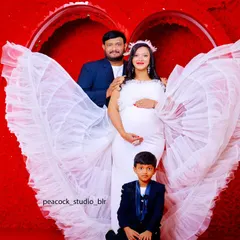 Celebrate your journey to motherhood with the whole family. This photo showcases a beautiful white maternity gown with dramatic ruffled wings, with coordinating outfits for your partner and child.