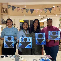 A group of friends proudly holding up their geometric abstract paintings, all with a similar theme but unique personal touches.
