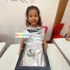 Look at that happy face! She's so proud of the solar cooker she made. It's amazing to see kids realize they can harness the power of the sun with simple materials.