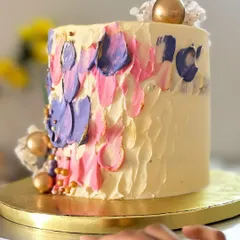This tall cake features a beautiful palette-knife painting effect with strokes of pink and purple buttercream, accented with gold leaf. It’s an edible piece of art, perfect for a stylish celebration.