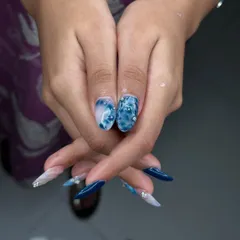 It's all in the details. This stunning blue marble and chrome nail set, complete with delicate rhinestone accents, showcases the advanced artistry our students learn.