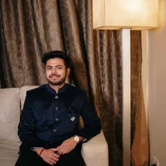 A handsome portrait of the groom seated and relaxed before the ceremony. The warm indoor lighting creates a comfortable and intimate atmosphere.