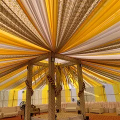 A grand mandap setup for a Haldi ceremony, created entirely with fabric drapes. The canopy of yellow, white, and brown printed fabric creates a spectacular visual from below.