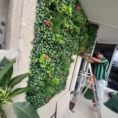 Here you can see me carefully attaching the final pieces to an artificial green wall. I make sure every panel is secure and the flowers are placed nicely for a great finish.