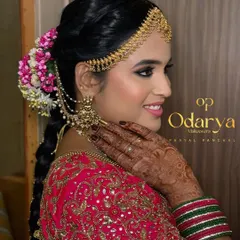 A beautiful side profile showcasing the harmony between the makeup, the intricate matha patti, and the floral bridal bun. The bold cat-eye makeup adds a touch of modern glamour to this traditional look.