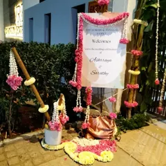 A welcome sign decorated with pink and white floral garlands, creating a traditional and festive entrance for the wedding guests.