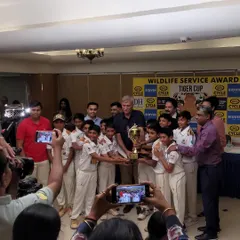 The entire U12 team receiving the prestigious Tiger Cup trophy from the legendary Mr. Roger Binny after a spectacular tournament performance.