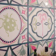 A closer look at the 'Tropical Tapestry' wallpaper. You can see the hand-drawn details in the ladybugs and palm trees, designed to look like individual, colourful tiles that fit together seamlessly.