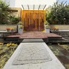A simple and beautiful outdoor Haldi setup. We used marigold garlands against a rustic wall, with the stage set over a water body for a serene and picturesque ceremony.