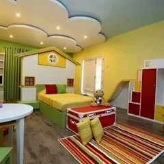 This vibrant kids' room is all about fun. It features a house-shaped bed, a slide, and a playful cloud-themed false ceiling, turning the bedroom into an indoor playground.