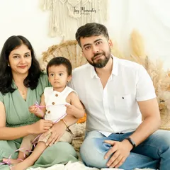 A calm and connected family portrait. The earthy green and white color palette complements the boho decor, creating a harmonious and peaceful image.