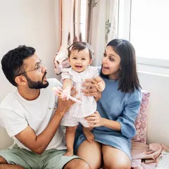 A happy family moment on the bed, celebrating their daughter's first birthday. These candid, at-home sessions are all about capturing genuine smiles and interactions.