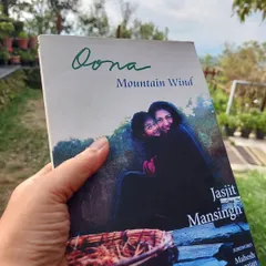 A participant holds a copy of 'Dona: Mountain Wind', a book that feels right at home in the Himalayas. Our library has a special section for mountain-themed literature.