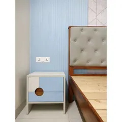 A contemporary bedroom design with a cool blue and grey color scheme. The bedside table features a unique geometric design with a circular cutout handle, adding a playful yet chic touch to the space.
