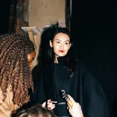 A candid moment of a model being interviewed backstage at London Fashion Week. This image captures the fast-paced media environment behind the runway.