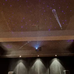 A closer look at the ceiling in this 7.1.2 Dolby Atmos theater. The starlight effect with shooting stars adds a magical touch, while the ceiling mounted Optoma laser projector delivers a crisp, bright image. The front speakers are positioned for optimal sound staging.