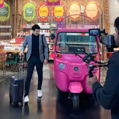 Posing next to a quirky pink auto-rickshaw inside the airport for a fun scene. I'm always ready to engage with the props and environment to create a memorable shot.