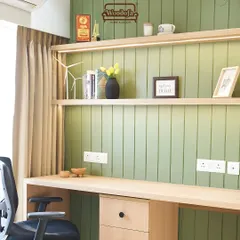 A simple and inviting study area. The olive green paneled wall adds color and texture, while the long wooden desk provides ample workspace for two. The open shelves are great for keeping books and decor.