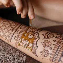 A macro shot showing the application of henna paste. You can see the texture of my natural paste and the process of filling in a floral design.
