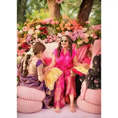 A bride enjoying her Mehendi ceremony, surrounded by a cascade of colorful flowers. The seating is designed to be both comfortable for the bride and a stunning photo opportunity.