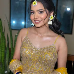 A bright, happy smile from a glowing bride-to-be. The makeup is kept fresh and luminous to match her vibrant yellow outfit and floral jewelry.