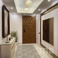 The view towards the entrance door of the foyer. The 3D wallpaper, designer door with a smart lock, and elegant chandeliers all work together to create a warm and luxurious welcome.