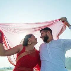 Using the bride's red dupatta to frame the shot, I created a playful and romantic image. The bright sunlight filtering through the fabric gives the photo a warm, happy glow, perfect for a pre-wedding memory.