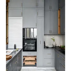 This galley kitchen is a great example of maximizing storage in a compact Mumbai flat. The grey shaker-style cabinets extend to the ceiling, and clever solutions like pull-out wicker baskets for vegetables ensure every inch is used effectively.