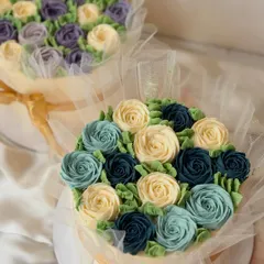 A stunning display of my buttercream flower work. These two mini cakes are designed to look like bouquets, with meticulously piped roses in shades of blue and purple, wrapped in delicate tulle.