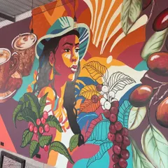 This coffee-themed mural is a celebration of color and culture. I painted a woman surrounded by coffee beans and plants to tell the story of where coffee comes from.