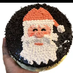 A classic Santa Claus face cake for Christmas. The design is piped with buttercream and surrounded by chocolate sprinkles.