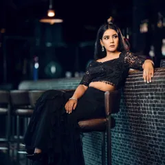 A moody, atmospheric shot of a model at a bar. The low light and specific pose create a sophisticated and modern vibe for this evening wear look.